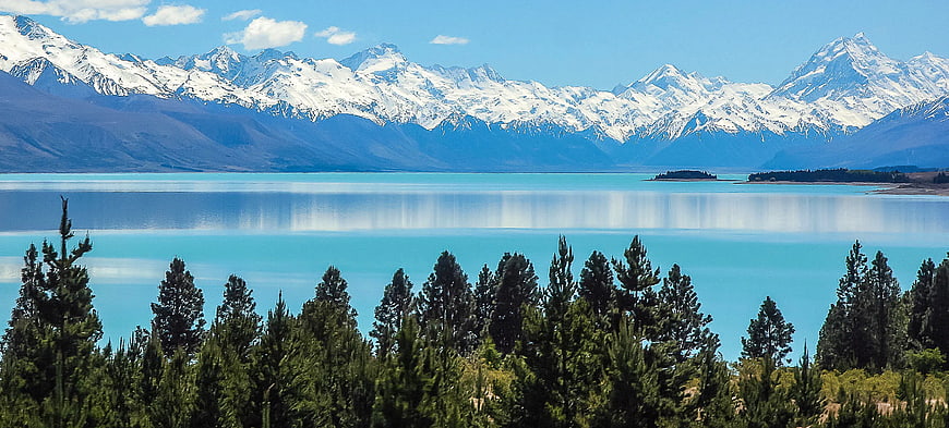 Snowy Mountains Reflected in Turquoise Lake with Pine Trees