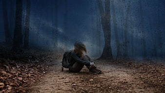 Lonely hiker sitting on a rainy forest path in the mist