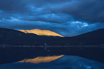 Dramatic Mountain Landscape with Golden Sunlight and Lake Reflection