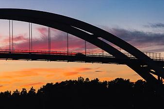 Silhouette of Arch Bridge Against Vibrant Sunset Sky
