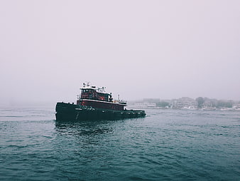 Red Tugboat on Foggy Ocean with Coastal Town