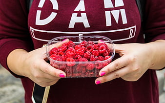 Woman holding container of fresh raspberries