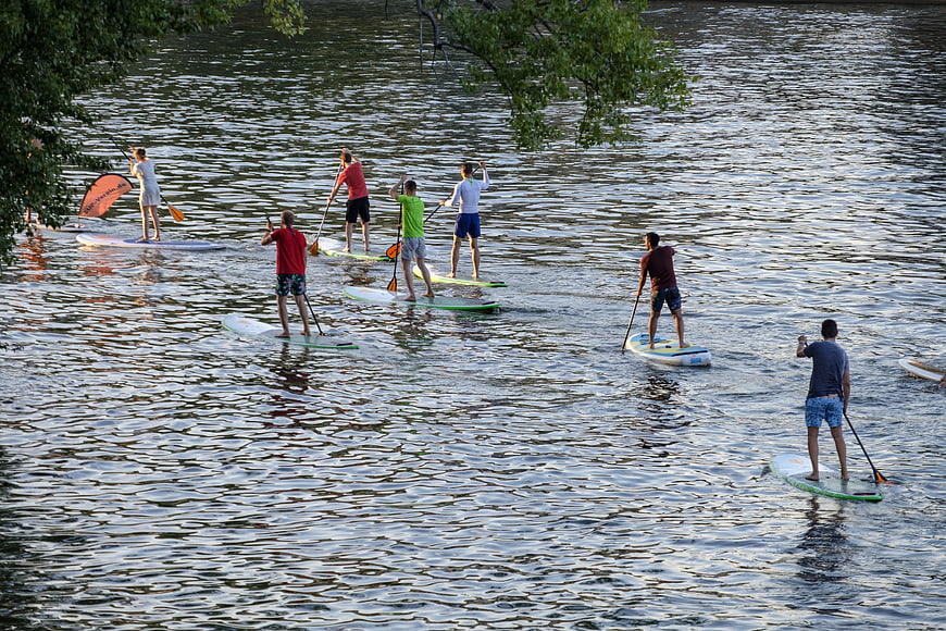 Group of People Stand Up Paddleboarding on a Calm Lake