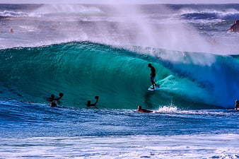 Surfer riding inside a massive turquoise ocean wave barrel
