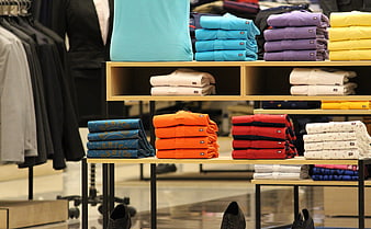 Colorful folded shirts on retail display shelves in clothing store