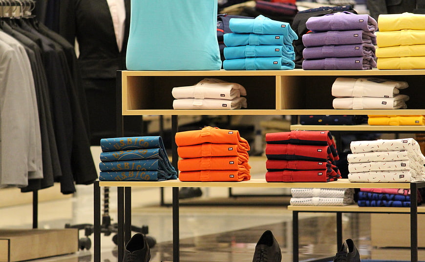 Colorful folded shirts on retail display shelves in clothing store