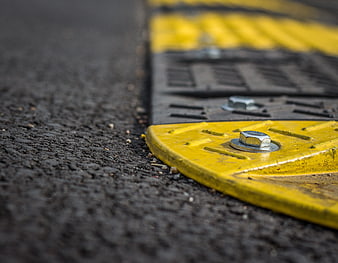 Close-up of yellow and gray steel manhole cover on asphalt