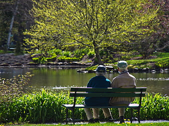 Senior Couple Sitting on Park Bench by Pond