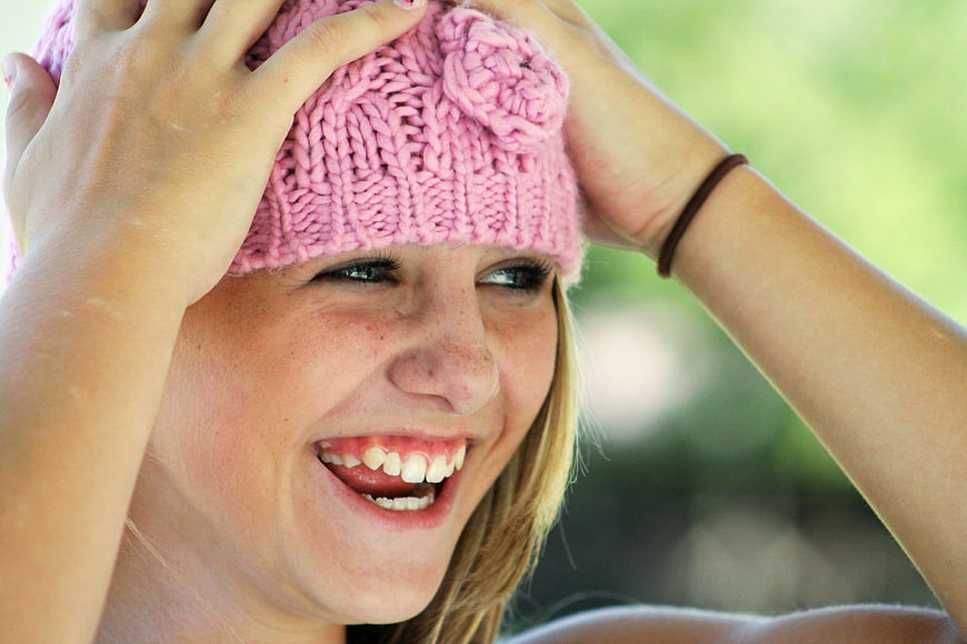Happy young woman laughing in pink knitted hat
