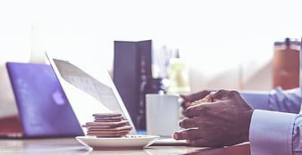 Businessman Eating Biscuits at Office Desk with Laptop