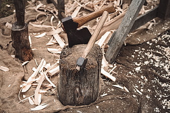 Woodworking axes embedded in a tree stump with wood shavings