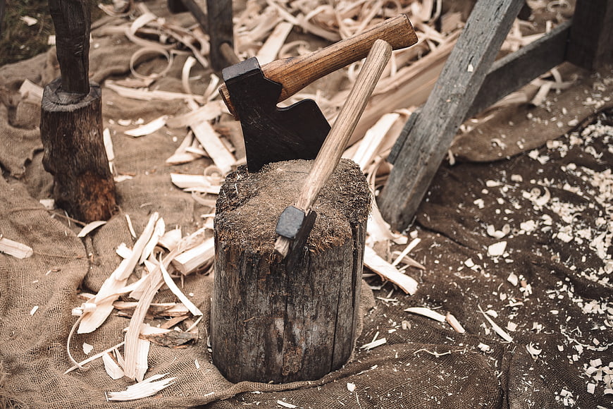 Woodworking axes embedded in a tree stump with wood shavings