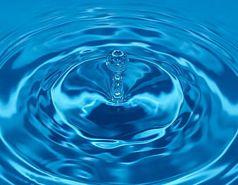 Close-up of a water droplet creating ripples in blue water