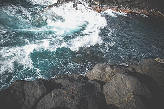 Aerial View of Turbulent Ocean Waves Crashing Against Rocky Cliffs