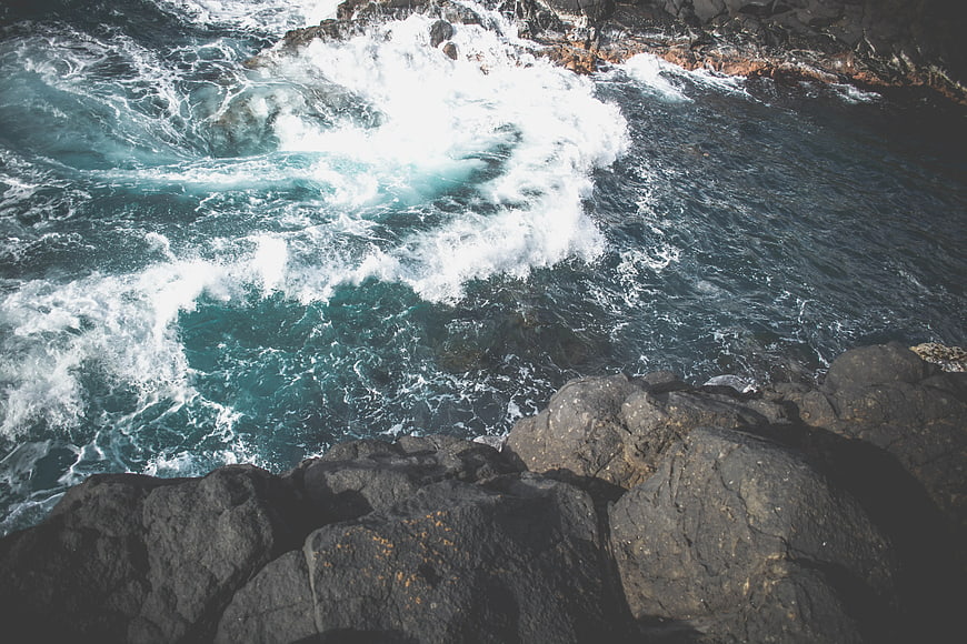 Aerial View of Turbulent Ocean Waves Crashing Against Rocky Cliffs