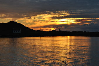 Golden sunset over calm sea with silhouetted coastal village