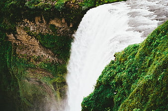 Aerial View of Powerful Waterfall Cascading Through Lush Green Gorge