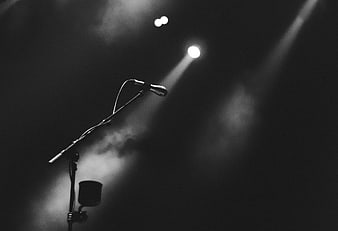 Black and white microphone on stage with spotlight and smoke
