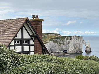Traditional half-timbered house with Etretat cliffs in background