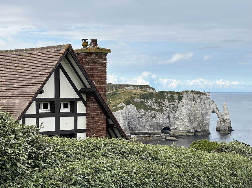Traditional half-timbered house with Etretat cliffs in background