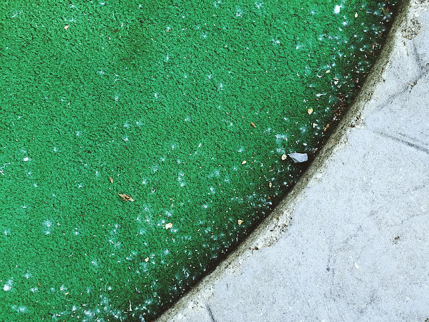 Close-up of green artificial turf and concrete edge