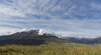 Panoramic mountain landscape with grassy foreground and blue sky