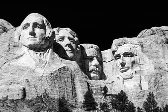 Black and white Mount Rushmore monument with pine trees