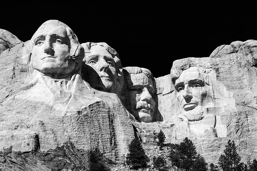 Black and white Mount Rushmore monument with pine trees