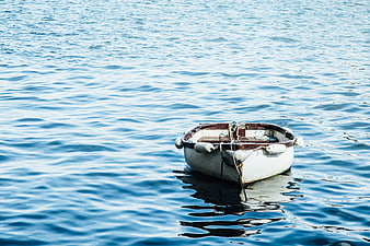 Small white boat floating on calm blue water