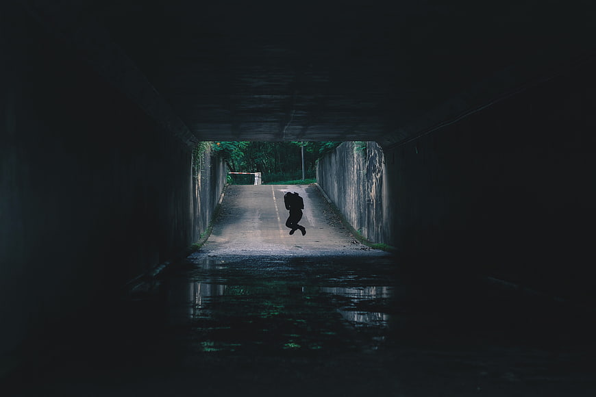 Silhouette of person jumping in dark tunnel
