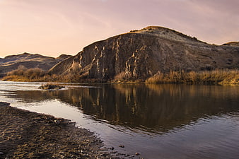 Serene River Flowing Past Rocky Canyon Cliff at Sunset