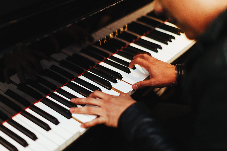 Close-up of hands playing Yamaha piano keys