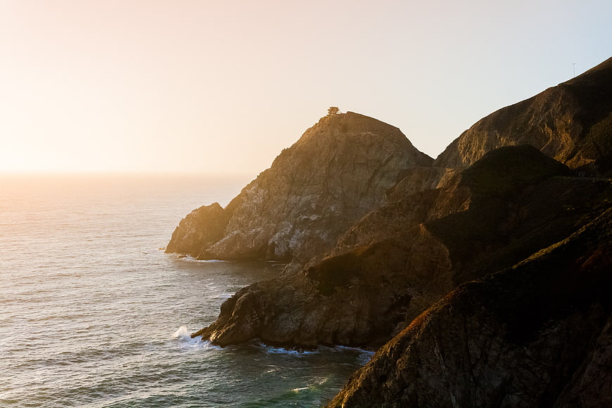 Dramatic Coastal Cliffs at Golden Hour with Solitary Tree