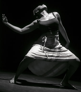 Black female dancer performing expressive contemporary movement in dramatic black and white