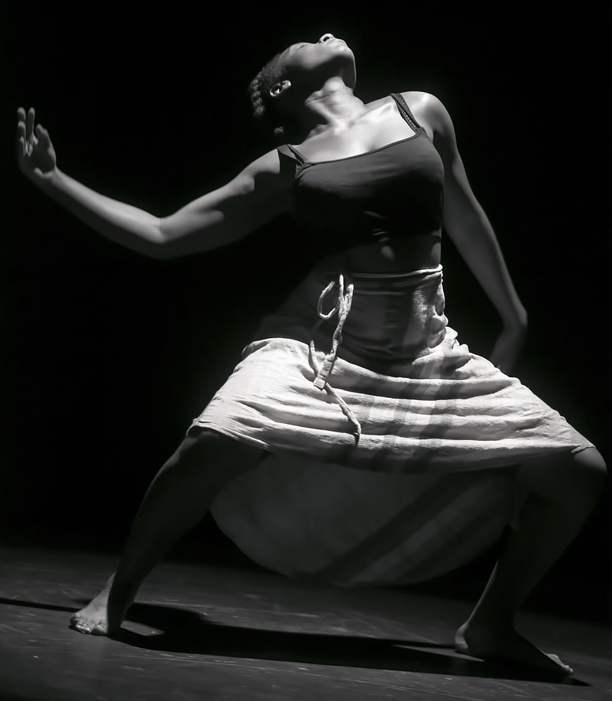 Black female dancer performing expressive contemporary movement in dramatic black and white