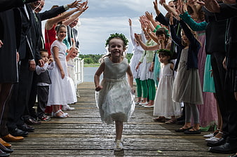 Young girl running down wedding aisle on wooden dock