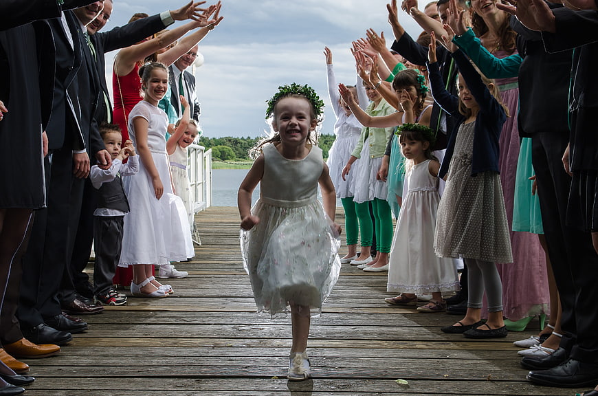 Young girl running down wedding aisle on wooden dock