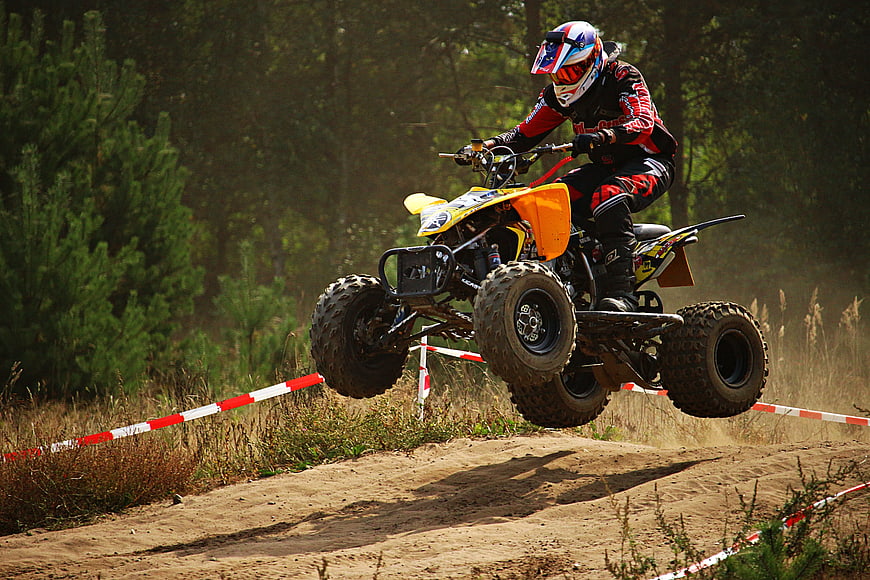 ATV Rider Jumping on Dirt Track in Forest