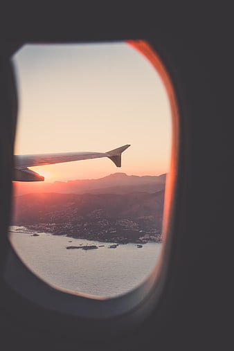 Airplane window view of coastal sunset over mountains