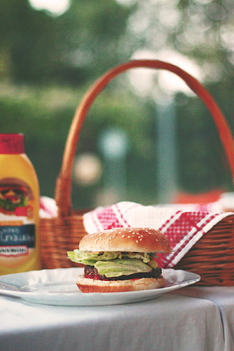 Delicious burger on plate with picnic basket and mustard