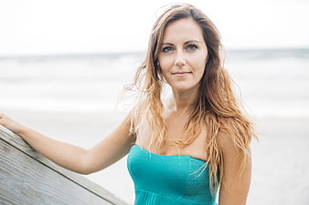 Young woman in teal dress posing on a beach
