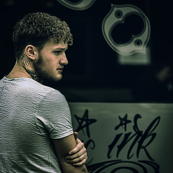 Pensive Man with Neck Tattoo in Urban Setting
