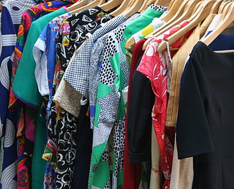 Colorful patterned dresses hanging on wooden hangers in a boutique