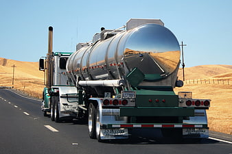 Green semi-truck with shiny tanker driving on highway