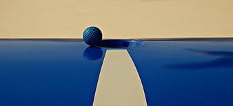 Blue mini golf ball on track near hole