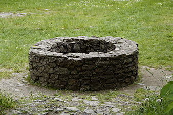Ancient Round Stone Well Structure In Green Pasture