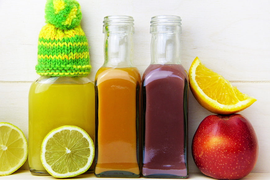 Three bottles of fresh fruit juice with winter hat and citrus