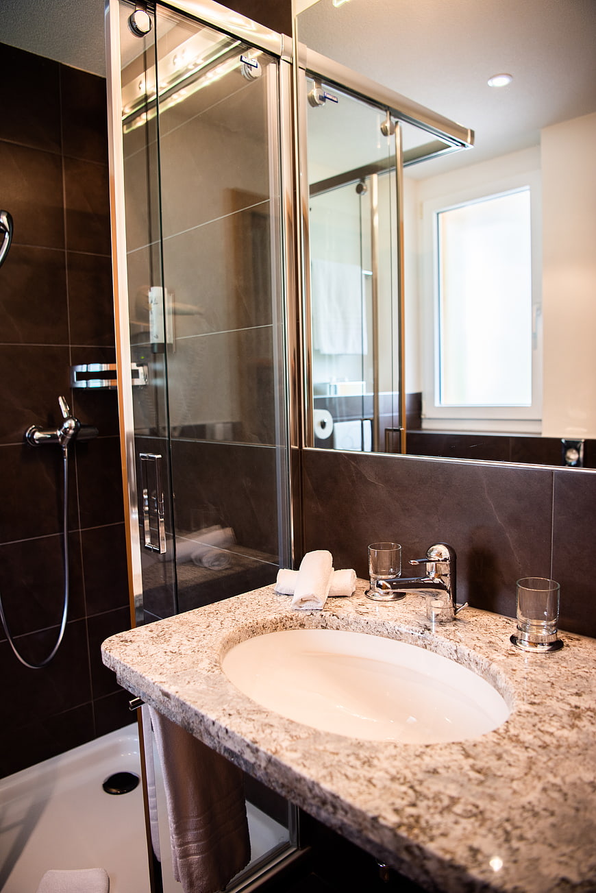 Modern bathroom interior with granite countertop and glass shower