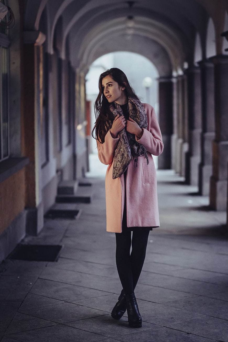 Woman in Pink Coat Walking Under Arched Portico