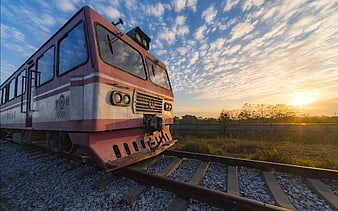 Vintage red train on tracks at sunset with blue sky